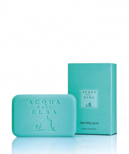 A turquoise bar of soap embossed with "Acqua dell'Elba" is paired with a matching rectangular box labeled "Arcipelago Donna." This set exudes a feminine scent characterized by citrus and apricot notes, beautifully showcasing a fresh, marine theme.