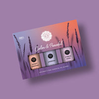 The Woolzies Calm & Peaceful Collection boxed set features three tranquil essential oils—Sweet Dreams, Unwind, and Stress Ease—set against a purple-orange gradient with lavender silhouettes. Brand: Woolzies.