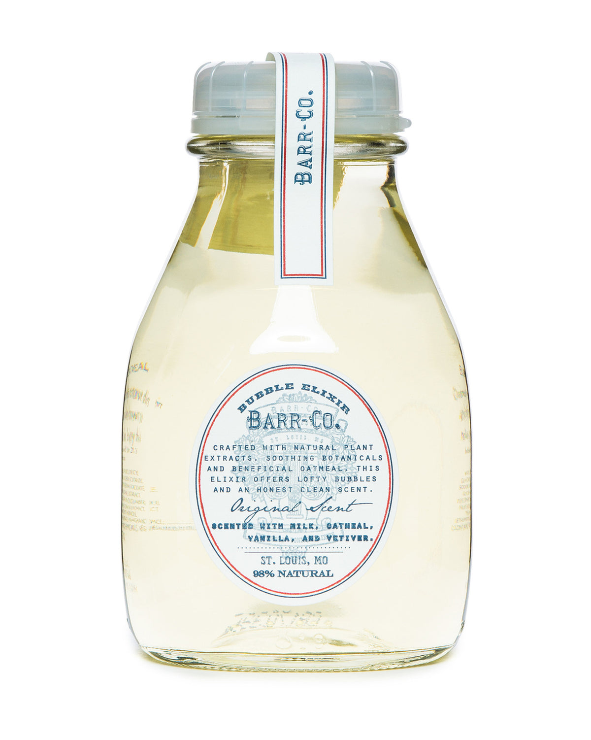 Clear bottle of Barr-Co. Original Scent Bath Elixir with a blue and red label, featuring a metal cap. The label highlights 98% natural ingredients, including soothing botanicals such as oatmeal, vanilla, and vetiver to nourish dry skin. Made in St. Louis, MO, it boasts a vintage design.