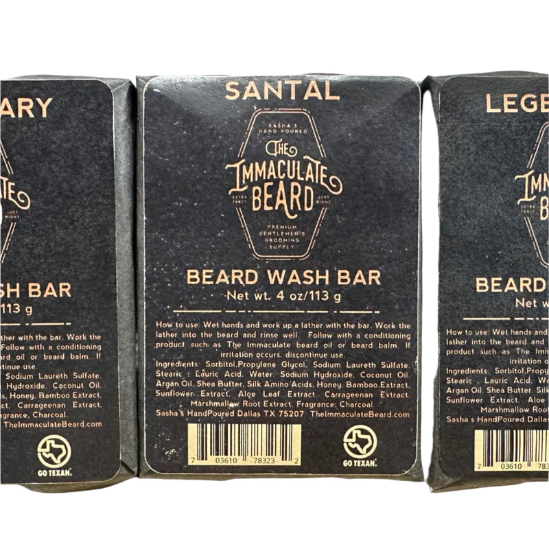 A rectangular 4 oz bar of The Immaculate Beard SANTAL Beard Wash Bar is shown in black packaging with gold and white text detailing its smoked sandalwood scent, ingredients, usage instructions, and brand information.
