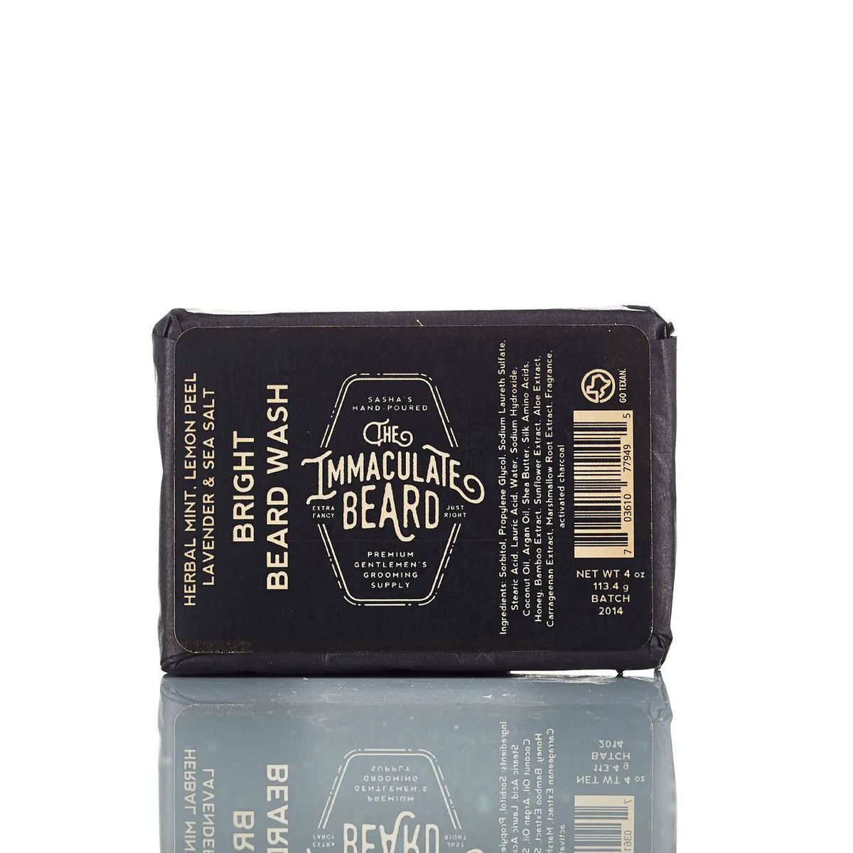 A bar of The Immaculate Beard BRIGHT Beard Wash Bar wrapped in black paper packaging with white and gold text, design details, product info, ingredients, and barcode from The Immaculate Beard.
