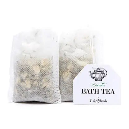 Two white mesh bags filled with dried herbs are tagged with a teapot illustration and the text "Bath Tea Single Bag - Breathe by Hampton Court." Ideal for relaxation, these bags are designed for soothing baths.