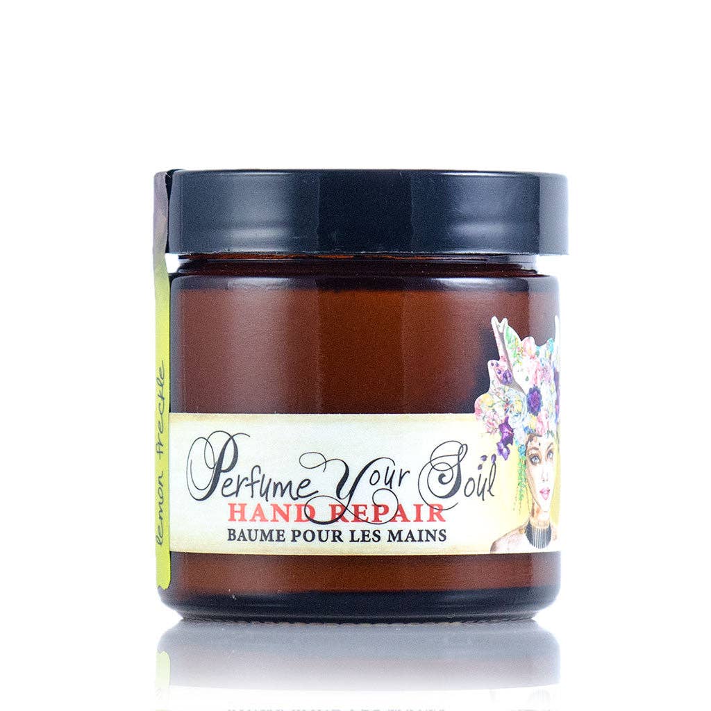 A brown jar with a black lid labeled "Barefoot Venus Lemon Freckle Hand Repair Balm." This plant-based hand balm features shea butter, a woman with a floral headpiece, and a yellow tag reading "Lemon Recipe.