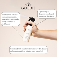 A hand sprays Goldie - Quick Spritz by Goldie. Callouts show it’s enriched with colloidal oatmeal, niacinamide, antioxidants, and manuka honey; triple-acting to soothe dog skin—deodorizes, hydrates like dog dry shampoo, cleans with micellar water.