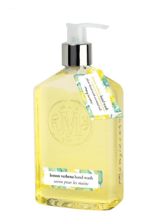 A clear plastic pump bottle filled with yellow liquid soap, labeled "Mangiacottie Lemon Verbena Hand Wash" and "savon pour les mains." Featuring an embossed Mangiacotti logo and a tag attached to the neck with additional product details, this organic hand wash is enriched with essential oils.