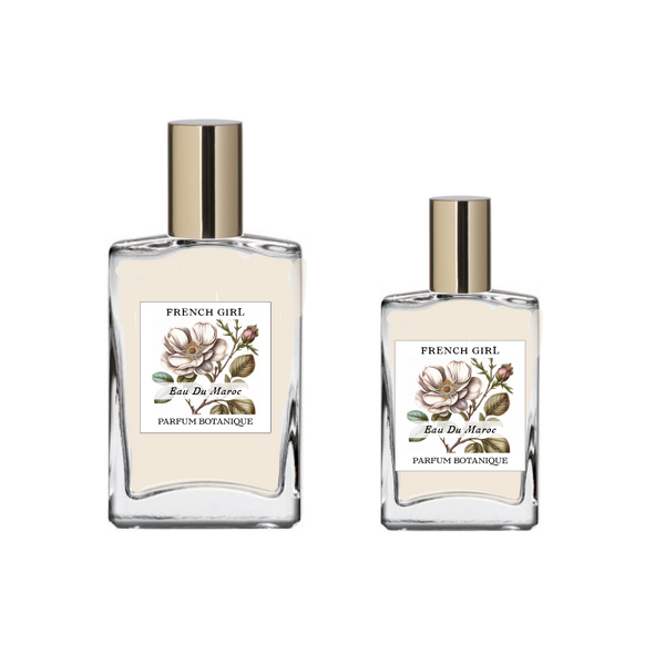 Two glass bottles labeled "FRENCH GIRL Eau Du Maroc Organic Vegan Natural Aromatherapy Perfume," featuring floral illustrations and gold caps, display this alcohol-free vegan scent made with essential oils, set against a plain white background.