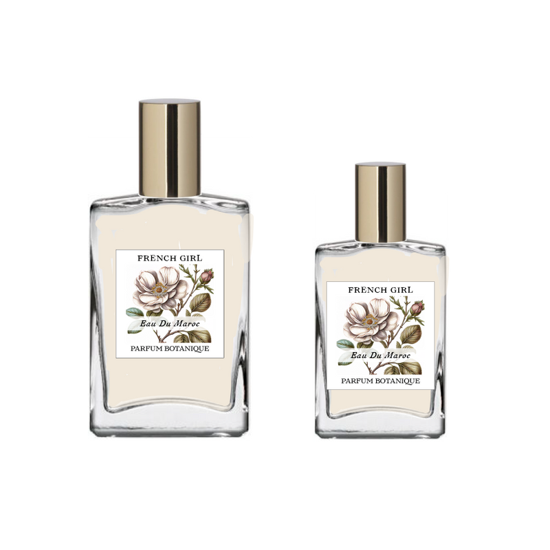 Two glass bottles labeled "FRENCH GIRL Eau Du Maroc Organic Vegan Natural Aromatherapy Perfume," featuring floral illustrations and gold caps, display this alcohol-free vegan scent made with essential oils, set against a plain white background.