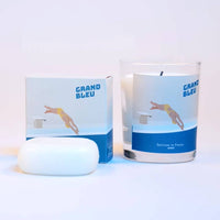 A white soap bar, a box with a diving figure and "GRAND BLEU" text, and the Senteurs De France “Le Grand Bleu” sea scented candle in glass, all displayed against a plain light background.