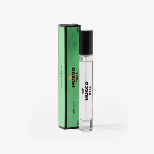 A clear glass bottle of Claus Porto Musgo Real Clássico 22 Eau de Toilette Travel Size by Claus Porto 1887 stands beside a tall, green, rectangular box with black accents and text, set against a white background.