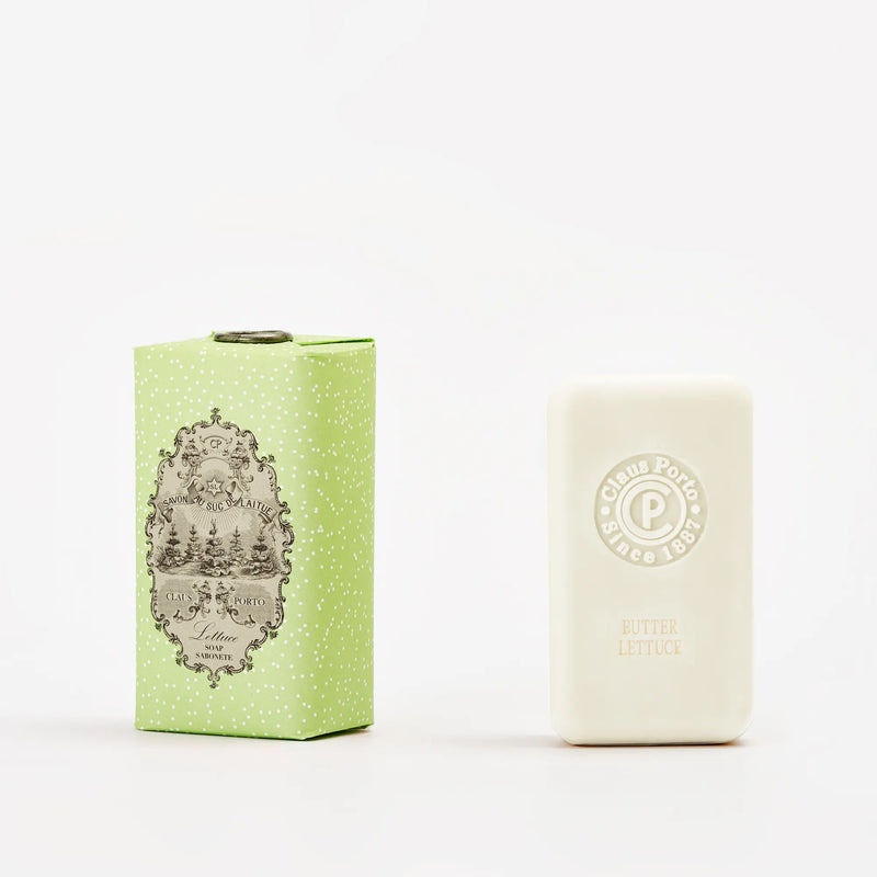 A light green patterned Claus Porto 1887 Classico Spring Lettuce Soap box stands by a white bar enriched with pistachio nut seed oil, embossed with "Claus Porto Butter Lettuce," on a plain white background.