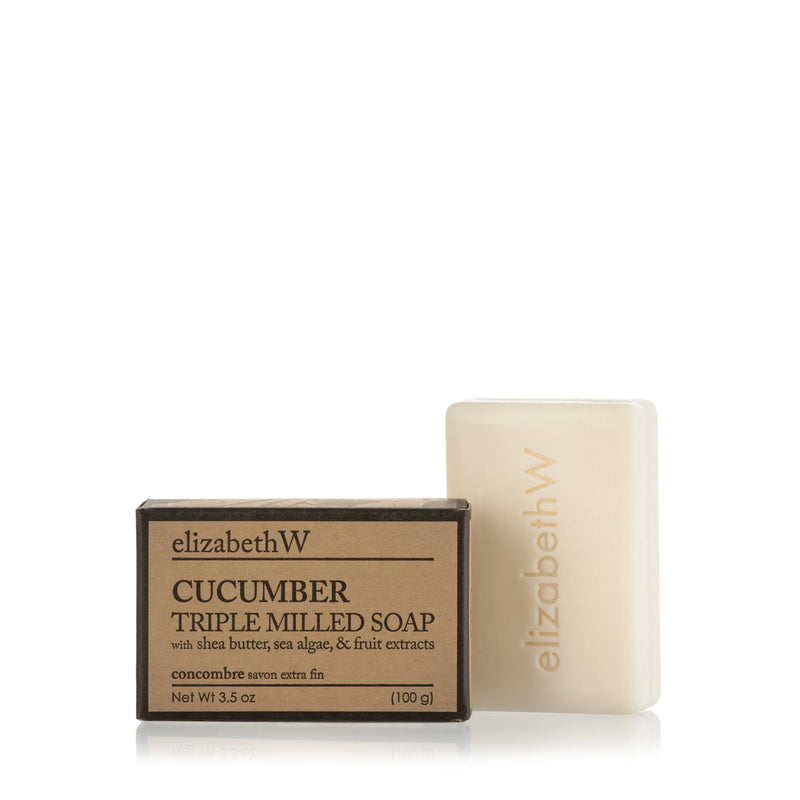 A bar of elizabeth W Purely Essential Cucumber Triple-Milled Soap, rich with plant-based ingredients, encased in minimalistic packaging. The brown box features black text detailing shea butter, sea algae, and fruit extracts. The creamy bar soap is beige and engraved with the brand name "elizabethW.