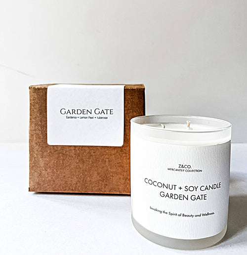 The Z&Co. Coconut + Soy Candle showcases its double wick in front of its brown box packaging, part of the Z&Co. French House Mercantile Candle Collection, featuring gardenia, lemon peel, and tuberose notes.