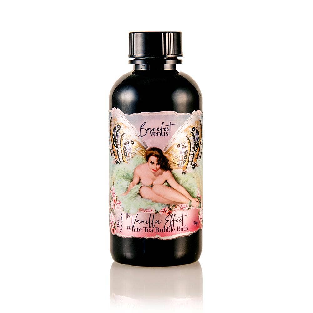 Bottle of Barefoot Venus The Vanilla Effect Bubble Bath with a vintage-style label featuring a fairy-like woman sitting amid flowers and butterfly wings. This black bottle boasts colorful, artistic design elements, enriched with eco-certified Oat Oil for a nourishing experience.