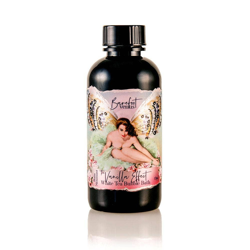 Bottle of Barefoot Venus The Vanilla Effect Bubble Bath with a vintage-style label featuring a fairy-like woman sitting amid flowers and butterfly wings. This black bottle boasts colorful, artistic design elements, enriched with eco-certified Oat Oil for a nourishing experience.