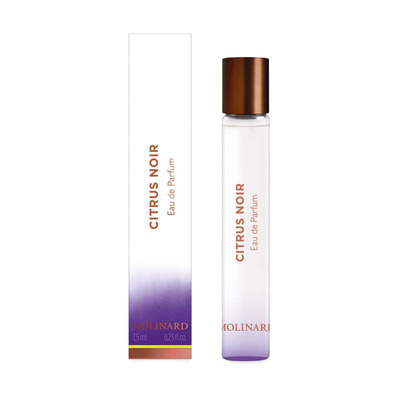 A cylindrical glass roll-on of Molinard Citrus Noir Eau De Parfum stands beside its white and purple gradient box, both with copper-toned text—an elegant Kalamansi unisex fragrance presentation by Molinard.