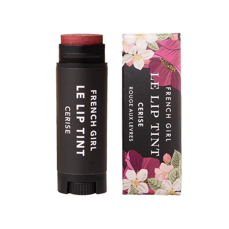 A tube of FRENCH GIRL - Tinted Lip Balm | Cerise rests beside its floral box, both adorned with white text. This vegan balm from FRENCH GIRL provides a hydrating treatment and a deep red tint for your lips.