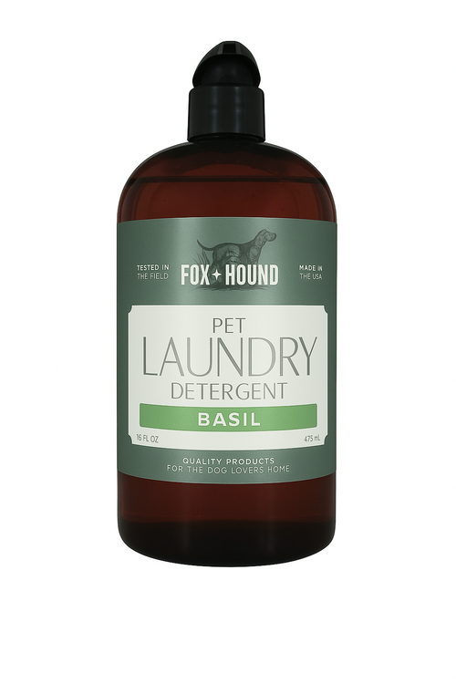 A 16 fl oz brown bottle of Fox + Hound Pet Natural Laundry Detergent Basil features a green and white label with a dog silhouette and product details.