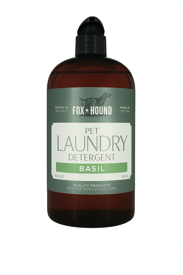 A 16 fl oz brown bottle of Fox + Hound Pet Natural Laundry Detergent Basil features a green and white label with a dog silhouette and product details.
