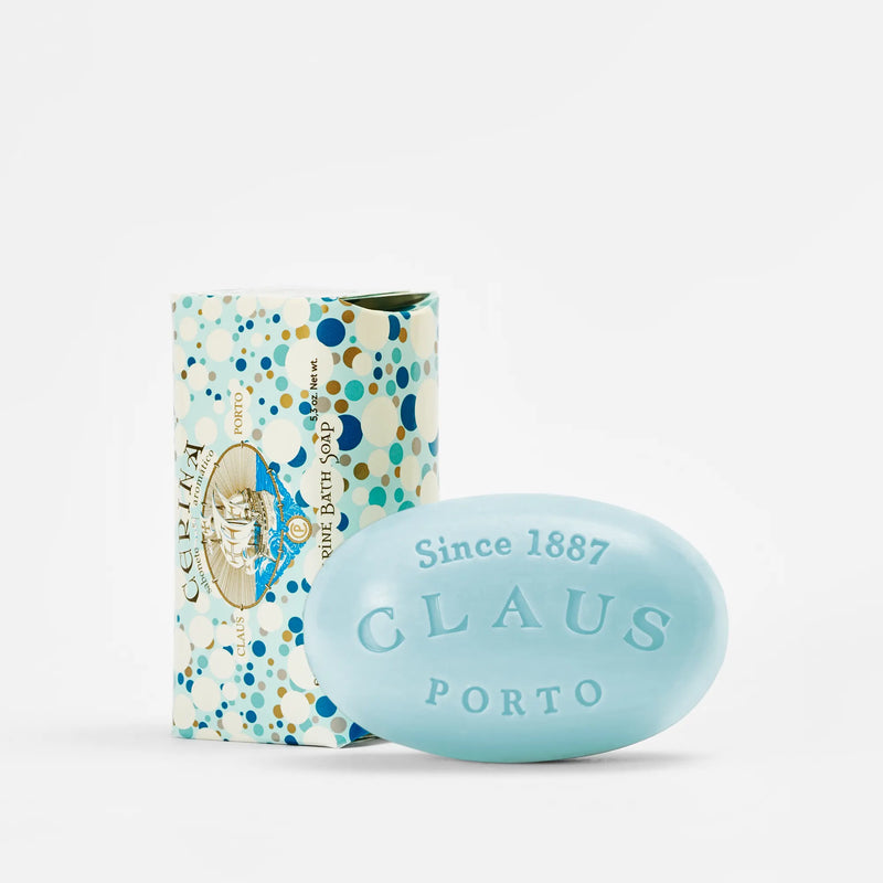 A Claus Porto 1887 Cerina Brise Marine Soap bar next to its packaging. The soap is light blue with the brand name embossed, and the box is decorated with colorful polka dots and vintage-style illustrations.