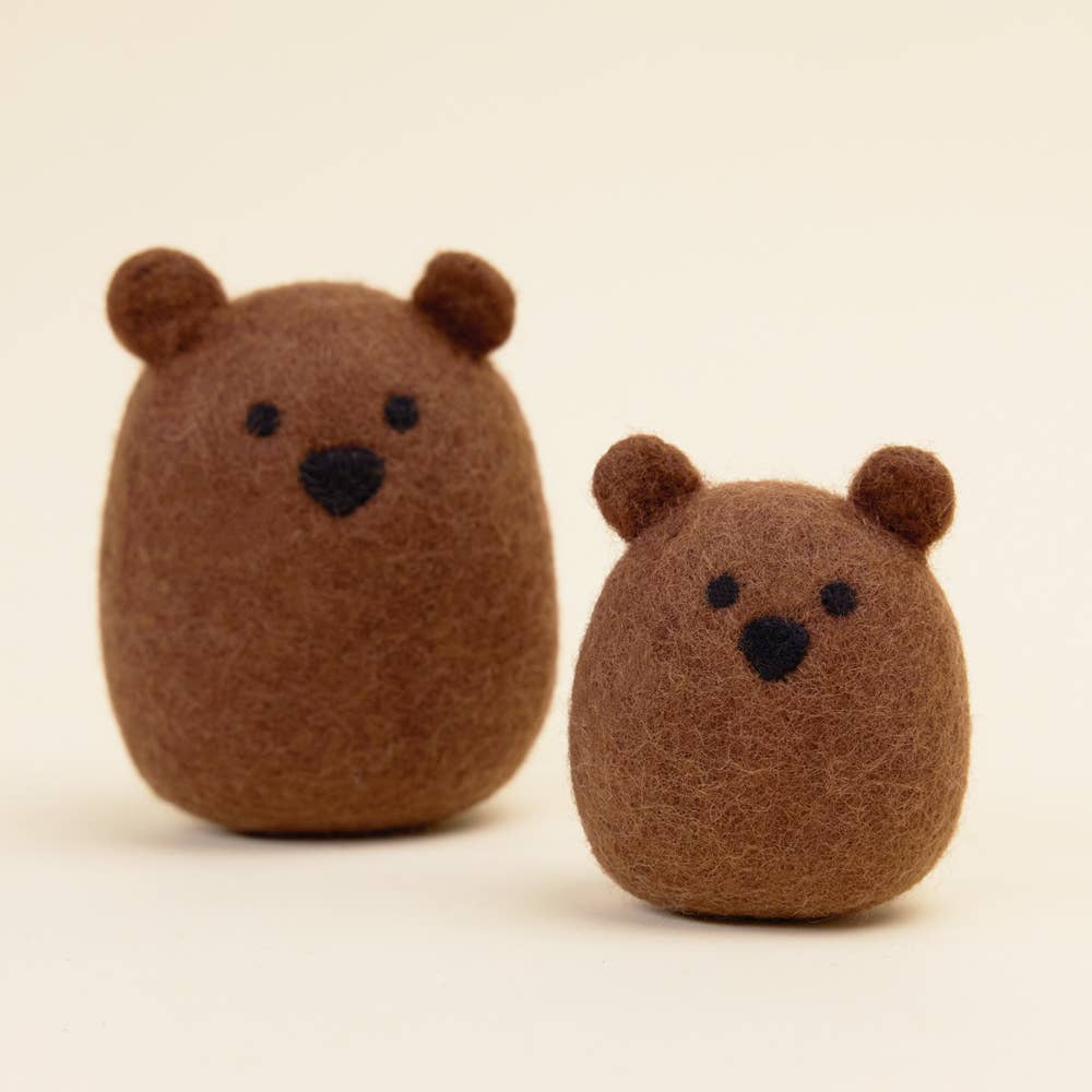 The MODERNBEAST Wool Brown Bear Dog Toy by MODERNBEAST features two small, brown, felted bears with simple black eyes and noses—one larger than the other—ideal as a charming and eco-friendly decorative accent or dog toy.