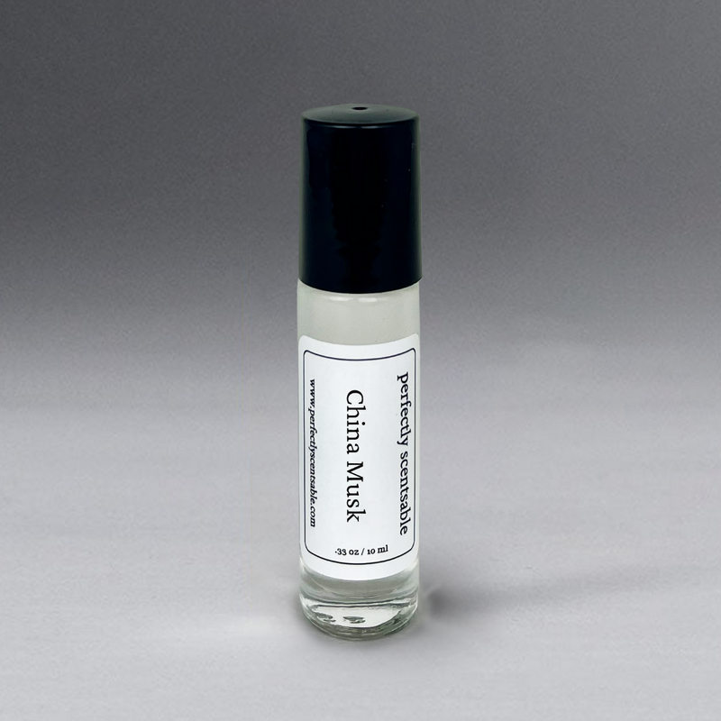 A small glass bottle with a black cap labeled "Perfectly Scentsable China Musk Perfume Oil - Rollerball," containing 0.33 oz (10 ml) of liquid. This timeless, gender-neutral fragrance stands upright against a gradient gray background.