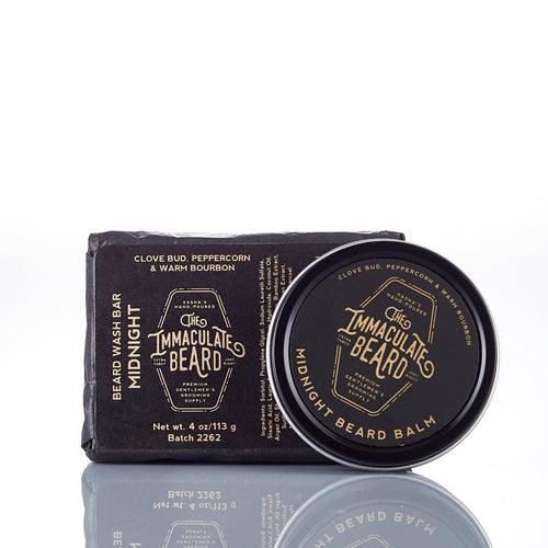 A black bar of beard wash and a round tin of The Immaculate Beard MIDNIGHT Beard Balm, both labeled with gold text. Scented with clove bud, peppercorn, and warm bourbon for premium natural care and medium hold.