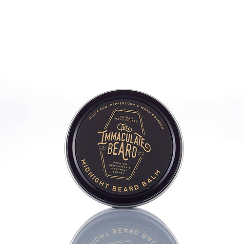 A round tin of The Immaculate Beard MIDNIGHT Beard Balm rests on a white background. Its black label with gold text notes clove bud, peppercorn, and warm bourbon scents—ideal for natural beard care and medium hold.