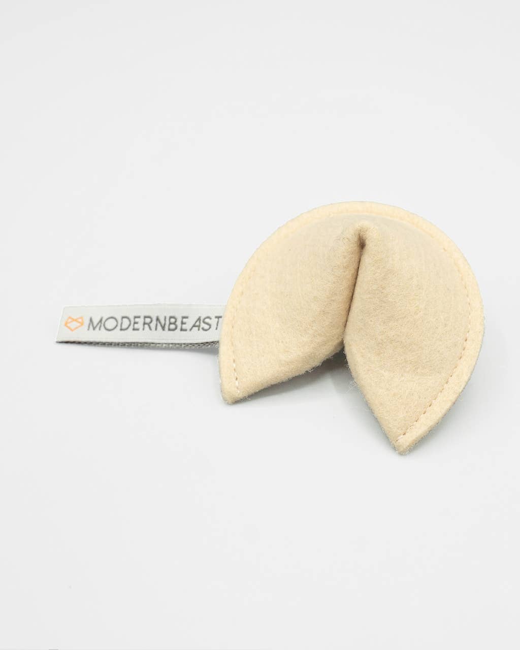 The MODERNBEAST Kitty Fortune Cookie Organic Catnip Cat Toy is a beige eco-felt cat toy with a "MODERNBEAST" label, filled with organic catnip and shown on a plain white background.