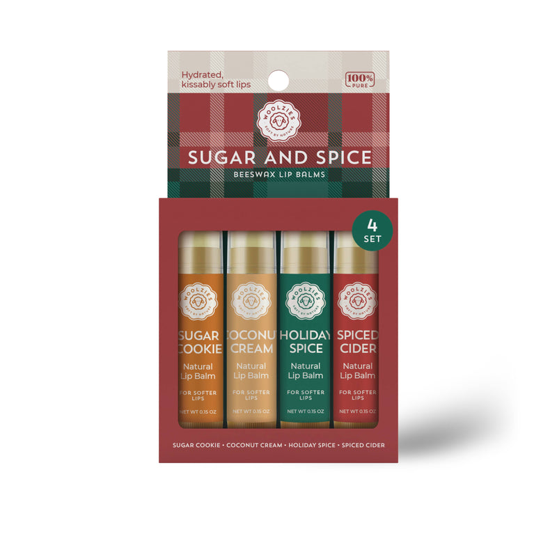 A four-pack of Woolzies Sugar and Spice Lip Balm Set Of 4 made with natural ingredients, displayed in a box with flavors labeled as sugar cookie, coconut cream, holiday spice, and sp.