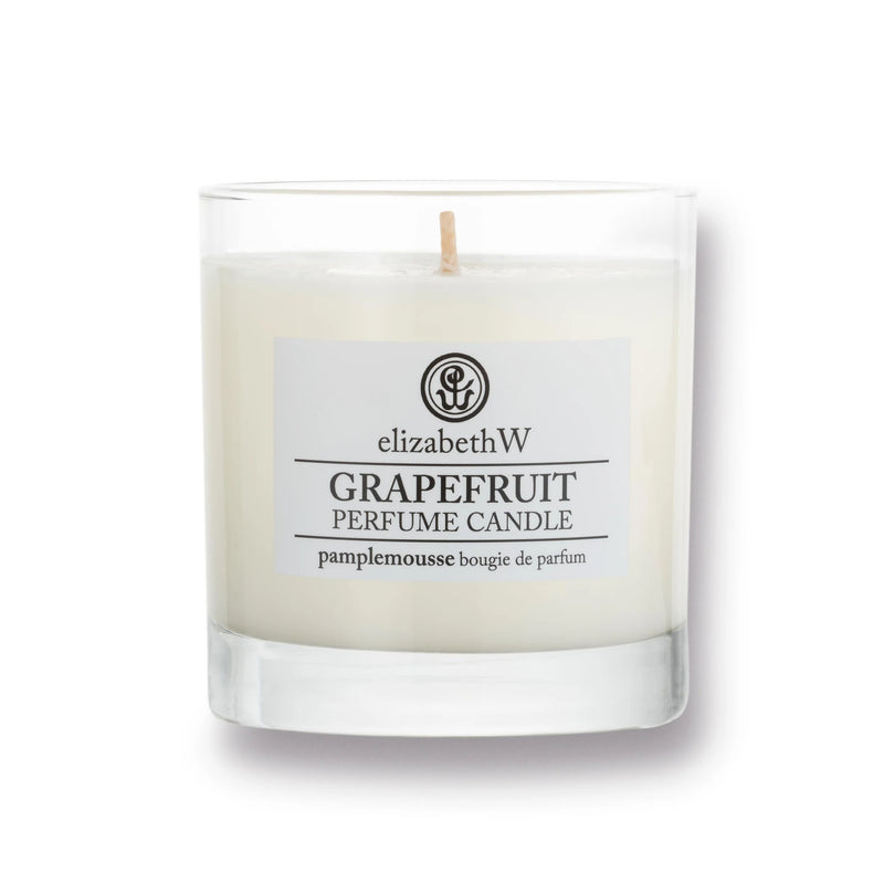 A white grapefruit candle in a clear glass container with a centered wick. The label reads, "elizabeth W Purely Essential Grapefruit Candle" in English and "pamplemousse bougie de parfum" in French. Enjoy its long-lasting fragrance crafted from premium soy wax.