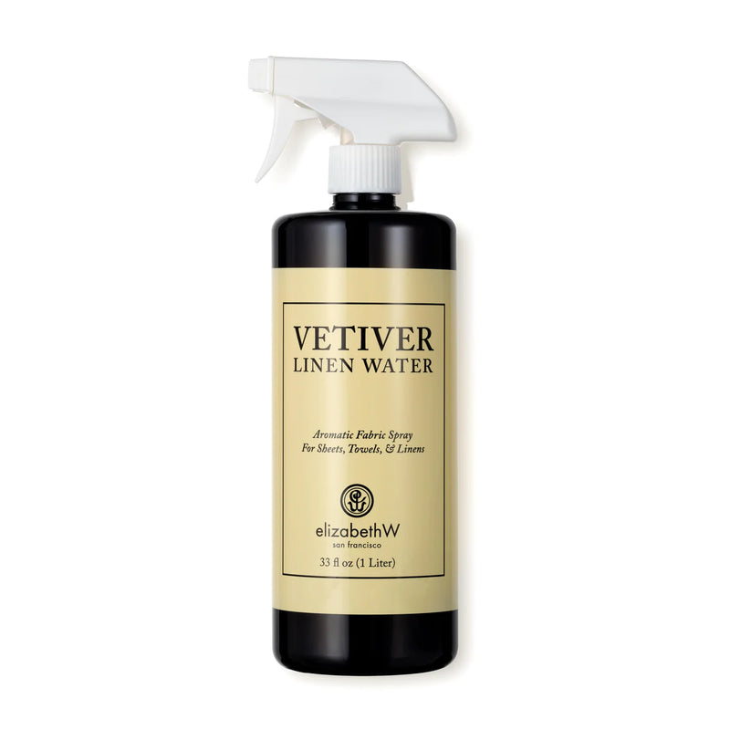 A black bottle of elizabeth W Signature Vetiver Linen Water with a white spray nozzle. The label includes text for aromatic fabric spray usage and branding details, ideal for luxury bedding.