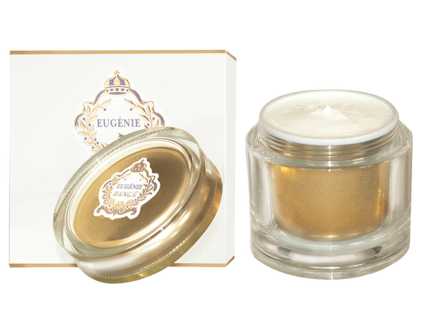 A clear glass jar of Rancé Eugenie Créme de Charme with a gold lid and white cream inside sits beside a matching white and gold box adorned with an ornate crest, evoking hints of subtle marine notes in its luxurious formula.
