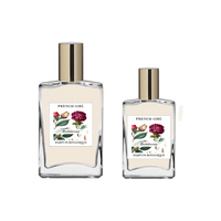 Two clear glass bottles with gold caps, labeled "FRENCH GIRL Damascena Rose Organic Vegan Natural Aromatherapy Perfume," each adorned with floral designs. These luxurious, alcohol-free perfumes are crafted with natural essential oils.