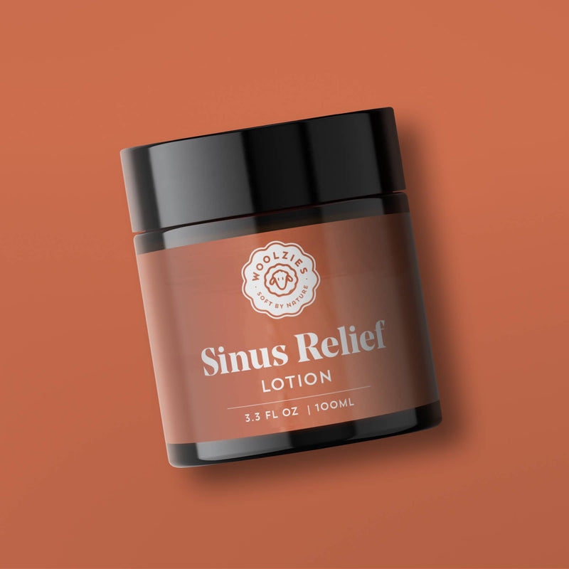 A brown and black jar labeled "Woolzies - Sinus Relief Lotion" sits against a solid brown background. Infused with essential oils like eucalyptus for clear breathing, the jar contains 3.3 fluid ounces (100 milliliters) of product. The label also displays a simple logo and text from Woolzies.