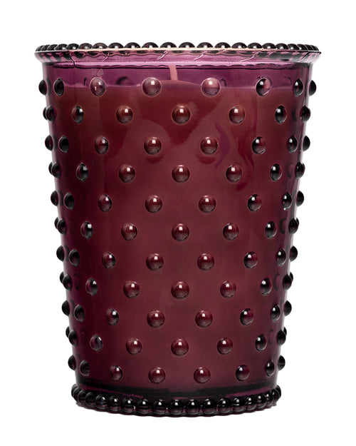 The Simpatico No. 98 Fig Hobnail Glass Candle by Simpatico features a purple glass holder with a hobnail texture and is filled with natural soy wax scented with fig.
