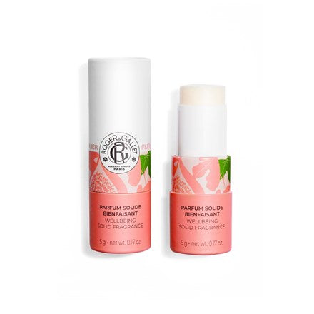The Roger & Gallet Fig Blossom Wellbeing Solid Perfume, in white and pink floral packaging, is shown with its cap off beside it. This 5g (0.17 oz), alcohol-free fragrance features natural ingredients.