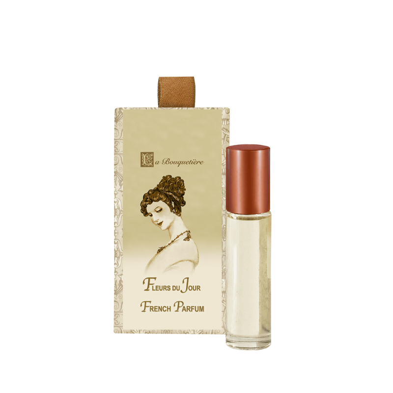 A vintage-style perfume package featuring an illustration of a woman’s profile and the words "fleurs du jour french parfum." Beside it is a small glass rollerball container filled with La Bouquetiere Fleurs du Jour/Marina Bleu Perfume Roller.