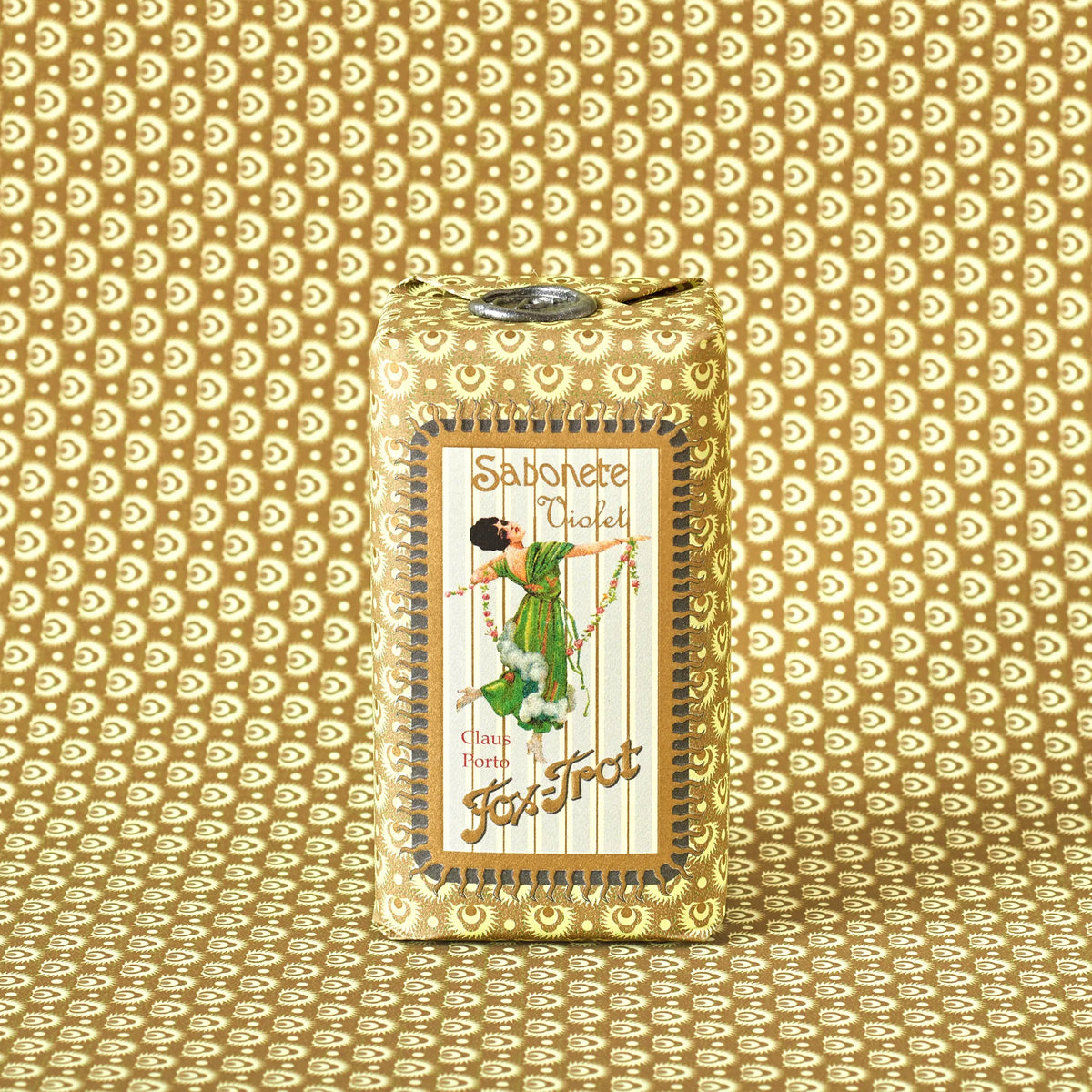 The Claus Porto 1887 Classico Fox Trot Violet Soap, wrapped in gold patterned paper with a dancing woman illustration, offers a classic violet scent and floral fragrance.