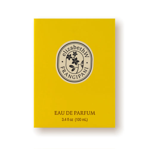 A bright yellow box of "elizabeth W Botanist's Scent Lab Frangipani Eau de Parfum." The label features a central circular emblem with a floral design, enhanced by hints of sandalwood. The fragrance volume is noted as 3.4 fl oz (100 mL).