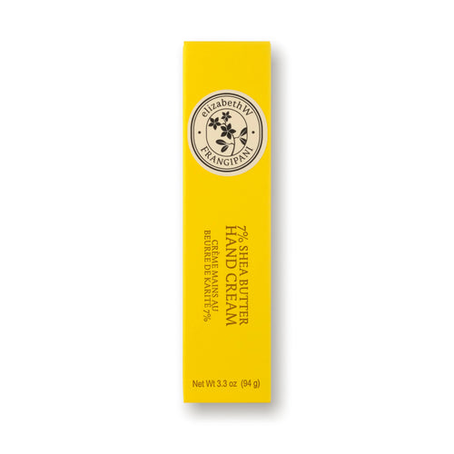 A tall, yellow box of elizabeth W Botanist's Scent Lab Frangipani Hand Cream, adorned with a black and white circular logo featuring a flower. The text reads "72% Shea Butter Hand Cream," guaranteeing it's intensely hydrating. The net weight is 3.3 oz (94 g), evoking a tropical bouquet essence.