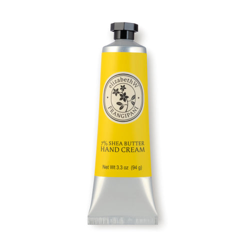 A 3.3 oz silver and yellow tube of intensely hydrating Frangipani Hand Cream, labeled "elizabeth W Botanist's Scent Lab Frangipani Hand Cream" with "7% SHEA BUTTER HAND CREAM" printed below. The tube also features an illustration of a flower on the upper part of the label, evoking a tropical bouquet.