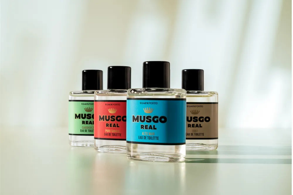 The Claus Porto Musgo Real Gift Set Hands Up Mini EDTCla by Claus Porto 1887 features four mini bottles, each with a different colored label—green, red, blue, and beige—arranged in a row, ideal for men’s fragrance gifting.