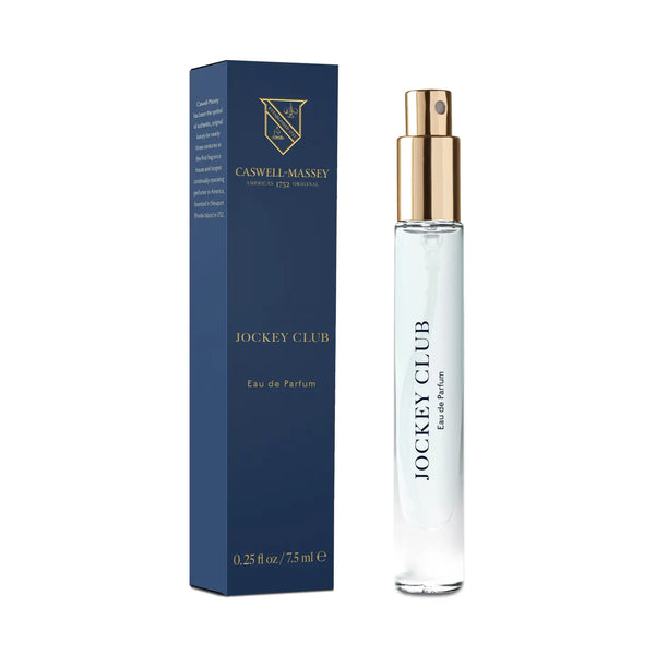 A Caswell-Massey Jockey Club Eau De Parfum 7.5mL bottle is displayed beside its navy box with gold accents. The clear bottle has a gold spray top and black labeling, showcasing this classic men’s fragrance from Caswell-Massey.
