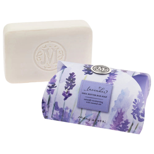 A white guest bar embossed with an "M" sits beside a floral box labeled "Mangiacotti Lavender Shea Butter Guest Bar Soap 6 oz.," crafted by Mangiacotti with natural ingredients for a soothing experience.