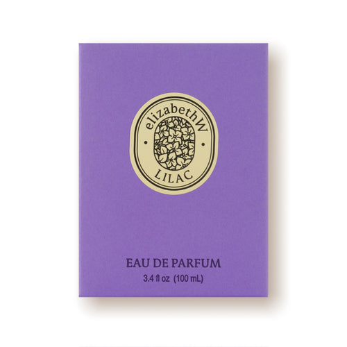 The elizabeth W Botanist's Scent Lab Lilac Eau de Parfum comes in a purple rectangular box adorned with a gold oval emblem featuring intricate designs and the text "elizabethW LILAC." Below the emblem, it reads "EAU DE PARFUM 3.4 fl oz (100 mL).