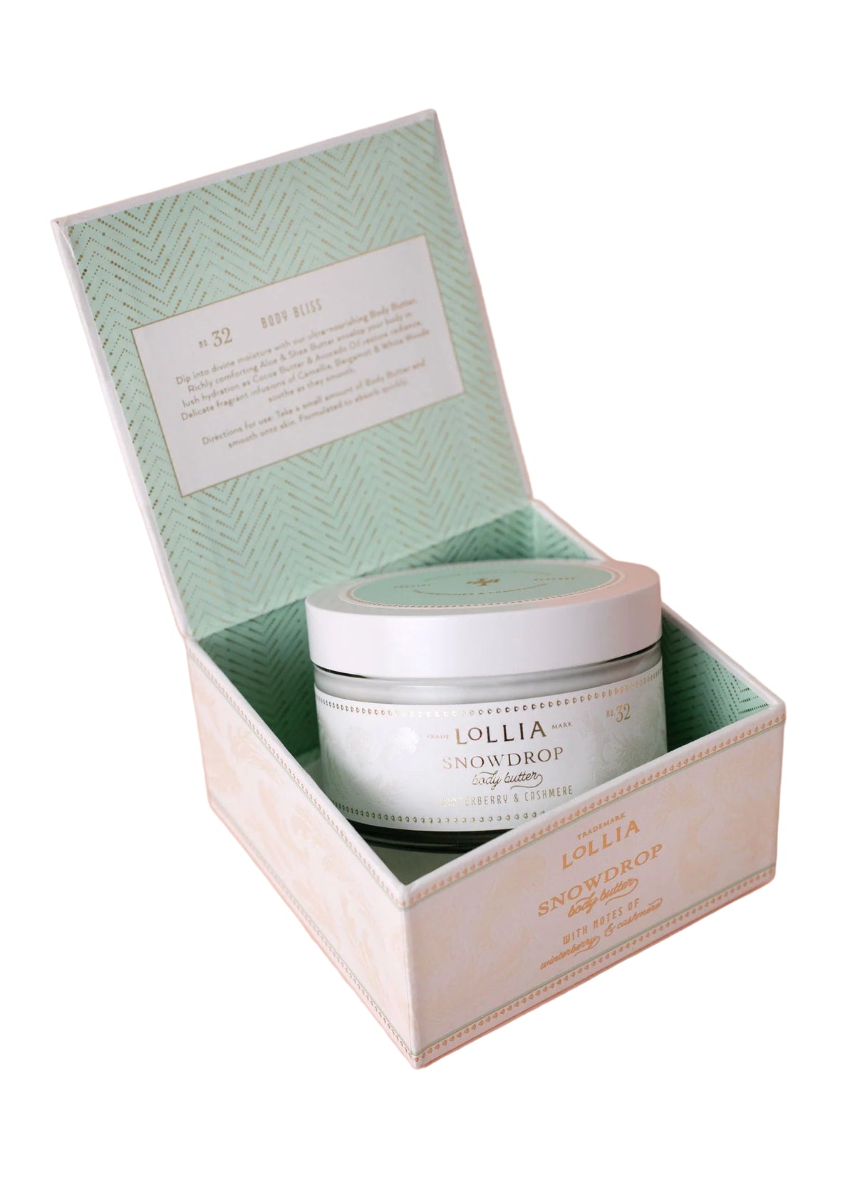 An open pastel green and white box reveals a round jar of Lollia Snowdrop Body Butter by Hampton Court Essential Luxuries & The Lavender Shop, labeled No. 32, on a pale pink background. The inner lid features a printed description.