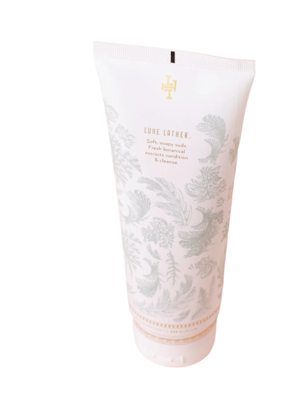 A white tube of Lollia Snowdrop Perfumed Shower Gel by Margot Elena, featuring light gray botanical illustrations and gold text, stands upright against a white background.