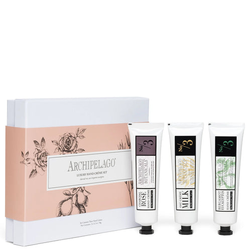 The Archipelago Luxury Hand Crème Trio Gift Set by Archipelago Botanicals features three hydrating hand creams in white tubes with black caps and distinct labels, presented before a pale pink and white floral-themed box.
