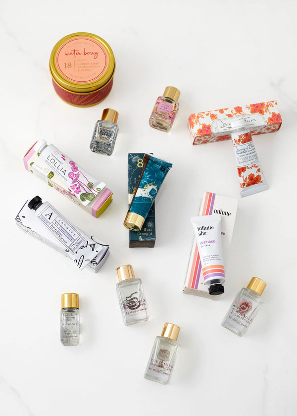 The Margot Elena Advent Calendar by Margot Elena features hand creams, a floral soap box, a tin candle, and more in floral-themed packaging—an ideal gift for fragrance lovers. Beautifully arranged on a white marble surface.