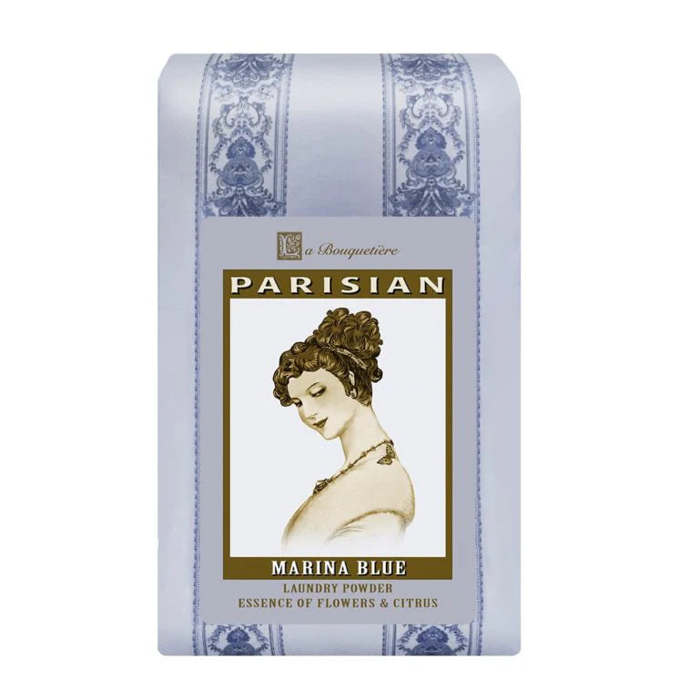 A light blue package of La Bouquetiere Fleurs du Jour / Marina Blue Laundry Powder features a vintage-style illustration of a woman with flowers and citrus essence. Elegant decorative patterns frame the artwork, while its bio-degradable formula offers a fresh-floral unisex fragrance.